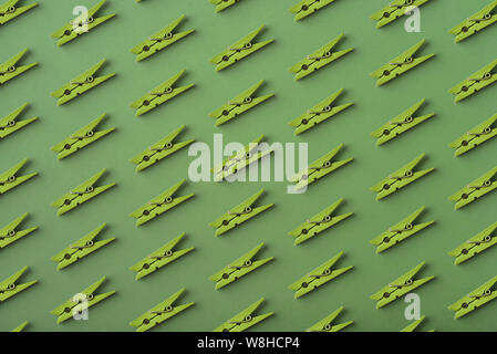 Pattern of green  clothes pins on the green background, top view Stock Photo