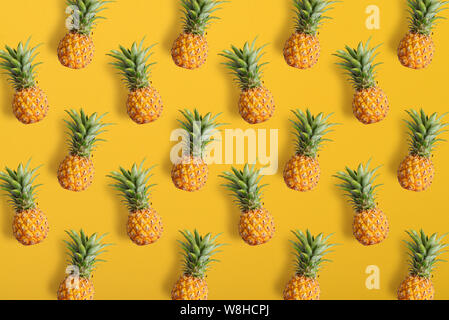 Colorful fruit pattern of fresh pineapples on yellow background, top view Stock Photo