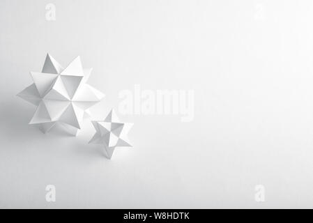 Two handmade paper polyhedrons on a white background. Stock Photo