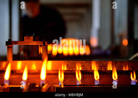 Mercury-in-glass thermometers are being heated in flames to have the necks of the glass tubes narrowed at the plant of Jiangsu Yuyue Medical Equipment Stock Photo