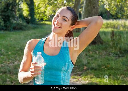 Young woman holding water bottle smiling, portrait. Stock Photo