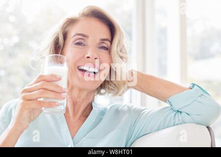 Mature woman smiling with glass of milk. Stock Photo