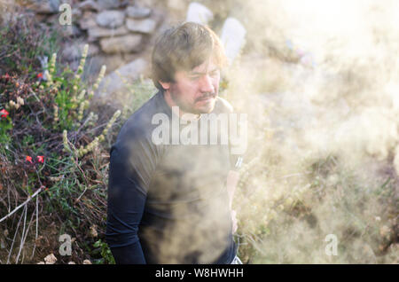 Survival Man is making bonfires in the winter forest, high on the Chiprac mountain - north of Lima - Peru Stock Photo