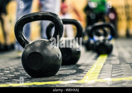 Different sizes of kettlebells weights lying on gym floor. Equipment commonly used for crossfit training at fitness club Stock Photo