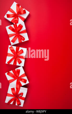 Christmas white gift presents on red background. Top view with copy space. Vertical Stock Photo