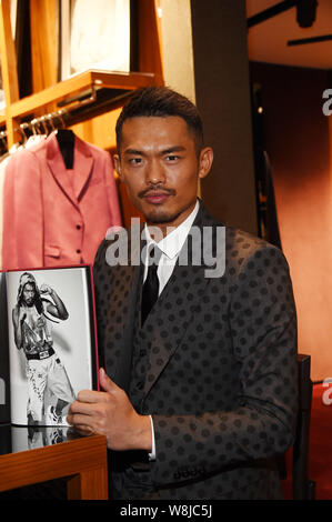 Chinese badminton star Lin Dan poses with his photo album at a signing event in Beijing, China, 20 March 2015. Stock Photo