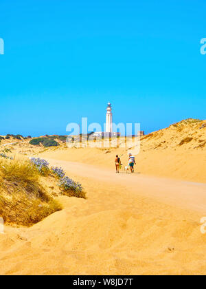 Tourists walking in a broad beach of fine sand dunes of The Cabo de Trafalgar Cape Natural Park. Los Caños de Meca, Spain. Stock Photo