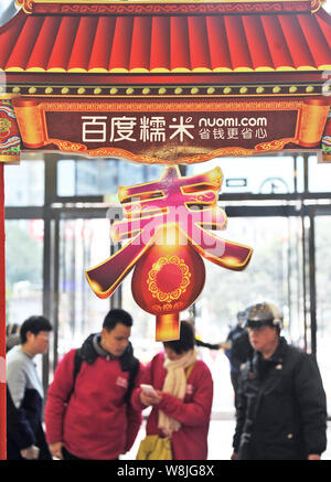 --FILE--Customers walk past an advertisement for online group-buying site Nuomi.com at a shopping mall in Fuzhou city, southeast China's Fujian provin Stock Photo