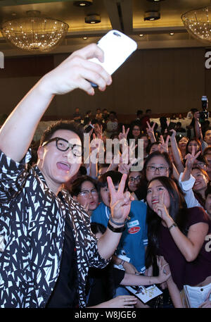 South Korean singer Jeong Soon-won, left, better known by his stage name The One, takes selfies with fans during a press conference for his Chinese al Stock Photo