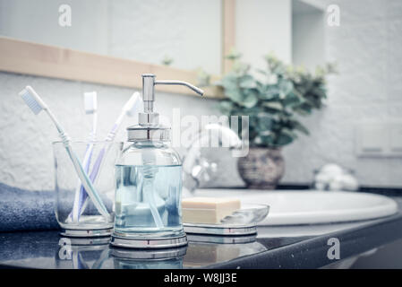 Bathroom sink and faucet with toothbrushes and soap dispenser Stock Photo -  Alamy