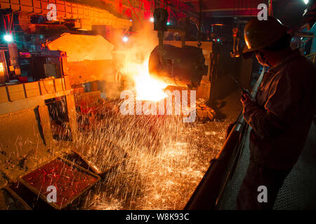 --FILE--Chinese workers watch molten steel being poured into a mould at a steel plant in Hangzhou city, east China's Zhejiang province, 5 August 2014.