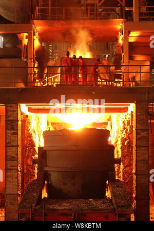 --FILE--Chinese workers survey the production of steel next to a furnace containing molten steel at a plant of Dongbei Special Steel Group Co., Ltd. i