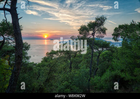 View from the woods on Buyukada of the sunset behind Heybeli island Turkey Stock Photo