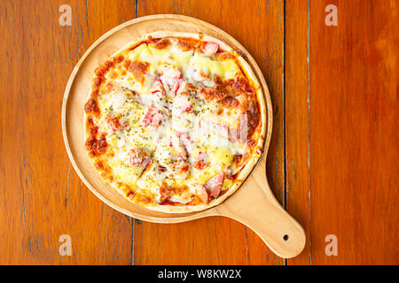Pizza  ham on the wooden tray is placed on the table. Stock Photo