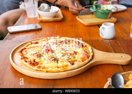 Pizza  ham on the wooden tray is placed on the table. Stock Photo