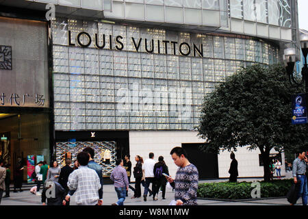 People walk past the Louis Vuitton (LV) boutique at the