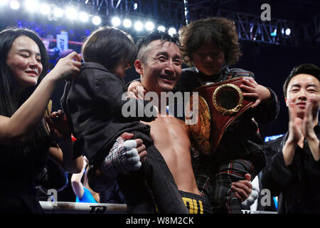 China's Zou Shiming, center, poses with his wife, left, and sons to celebrate after defeating Brizil's Natan Santana Coutinho during their bout in Sha Stock Photo