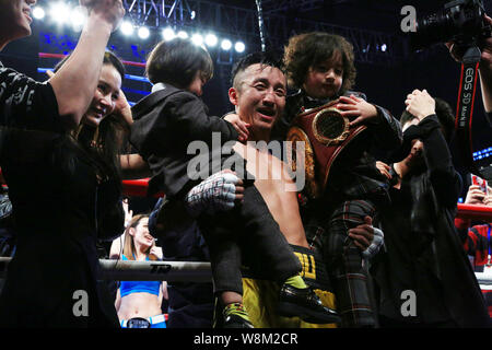 China's Zou Shiming, center, poses with his wife, second left, and sons to celebrate after defeating Brizil's Natan Santana Coutinho during their bout Stock Photo