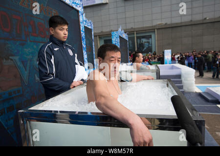 Chen Kecai, left, and Xiang Yong, two 'ice men' known for their abilities to withstand extreme coldness, immerse themselves in boxes filled with ice d Stock Photo