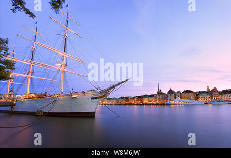 Scenic view of Stockholm's Old Town (Gamla Stan) at dusk with illuminated old ship on the foreground, Sweden Stock Photo