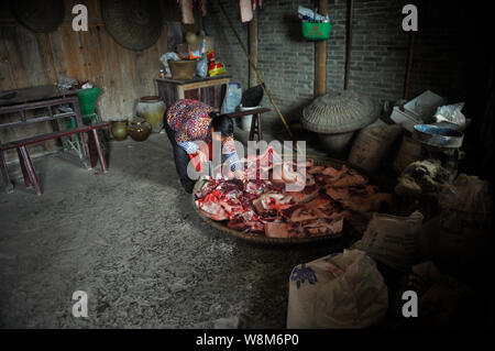 A Chinese villager picks meat from a butchered pig before hanging is up on the ceiling at home in preparation for the upcoming Chinese Lunar New Year, Stock Photo