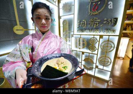 A waitress serves a bowl of noodles cooked by robots Koya and Kona at a ramen restaurant in Shanghai, China, 11 January 2016.   Robots are continuing Stock Photo