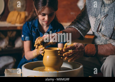 Pottery workshop. Grandpa teaches granddaughter pottery. Clay modeling Stock Photo