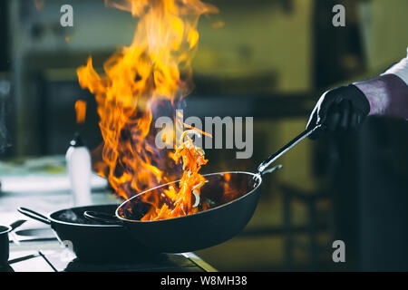 Chef is stirring vegetables in work on the kitchen. Stock Photo