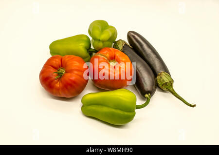 A group of fresh vegetables from green sweet peppers and  large red tomatoes and black- purple eggplants grown in Armenia lies on a white background Stock Photo