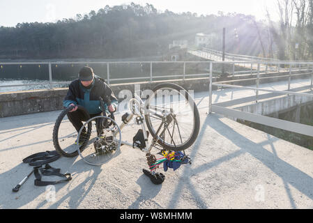 Man cyclist repairs a bicycle with flat tire during a trip. Concept of unforeseen and bad luck Stock Photo