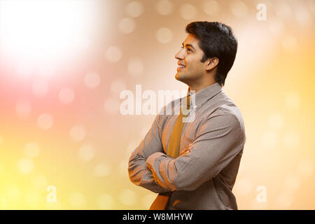 Businessman standing with his arms crossed and day dreaming Stock Photo