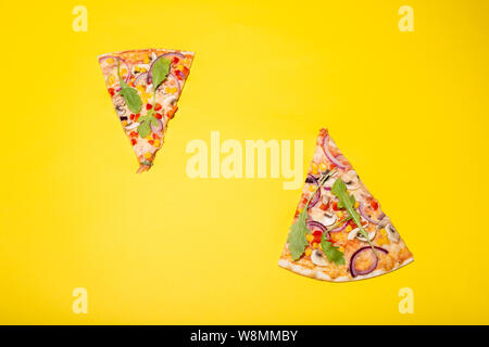 Flat lay photo of two pizza slices isolated on yellow background Stock Photo