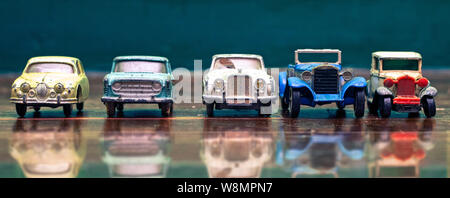 a line of retro toy cars parked on a old wooden floor with reflection Stock Photo