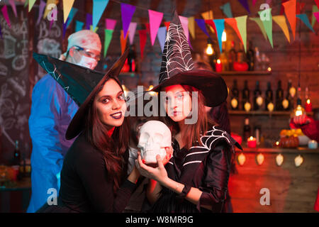 Crazy doctor and two beautiful witches celebrating halloween. Witches with beautiful dresses. Stock Photo
