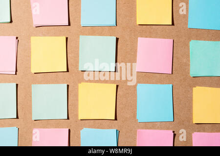 Multi colored notepads laying on a wooden plank board surface with copy space Stock Photo