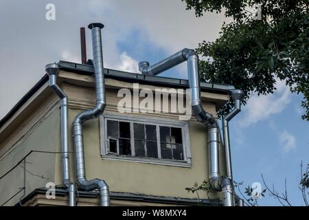 Metal ducts from the restaurant kitchen laid on the plastered wall. The courtyard. Site about architecture, kitchen, ventilation, air, communications. Stock Photo