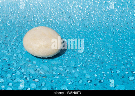 White single stone on blue water drops background Stock Photo