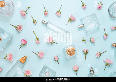 Perfume bottles and pink roses on blue background - top view Stock Photo