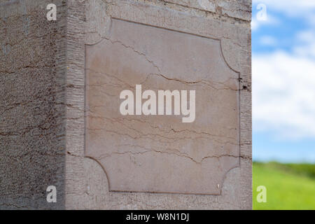 Rectangular ancient pillar, light stone plate of sandstone against background of summer field. Empty granite signboard with border, frame. Concept fra Stock Photo