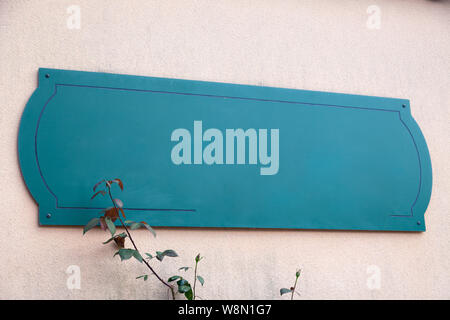 Empty sign on wall, green empty mockup plate with copyspace. Empty blank sign on blurry background. Advertising concept or logotype Stock Photo