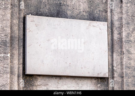 Closeup vintage rectangular shape stone aged plate, nameboard on gray textured wall. Concept place for lettering, text, copyspace Stock Photo