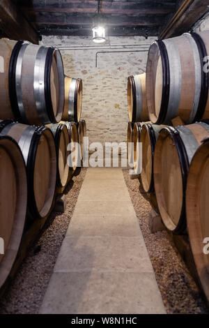 Wooden wine oak barrels stacked in straight rows in order, old cellar of winery, vaults. Concept brewery background, professional degustation, winelov Stock Photo