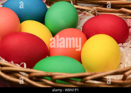 Large Easter eggs of different colors lie in a wicker basket. Horizontal photography Stock Photo