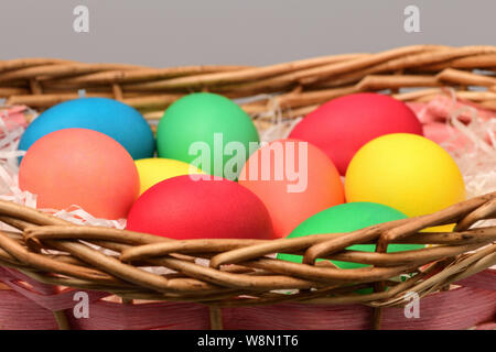 Easter eggs are colorful in a wicker basket on a gray background. happy Easter. Horizontal photography Stock Photo