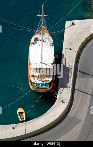 Old wooden sailing boat with lifeboat moored in Omis harbor in Croatia Stock Photo