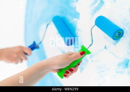 blue color painting wall with roller in hand. Stock Photo