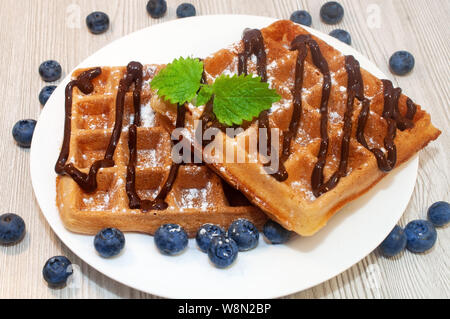 Belgian waffles on a plate with chocolate sauce and blueberries Stock Photo