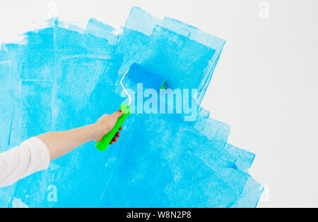 blue color painting wall with roller in hand. Stock Photo