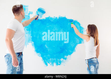 Happy couple painting walls in their new house ready for living together. Stock Photo