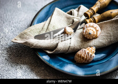 Marine cutlery set with shells and sea stars on grey concrete background with copy space Stock Photo